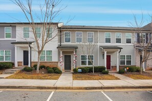A row of townhouses with a front porch, a mailbox, and a small garden area.