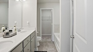 Un baño moderno con dos lavamanos, un espejo grande y una ducha a ras de suelo.