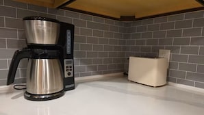 Una cocina con cafetera y tostadora sobre una encimera blanca.