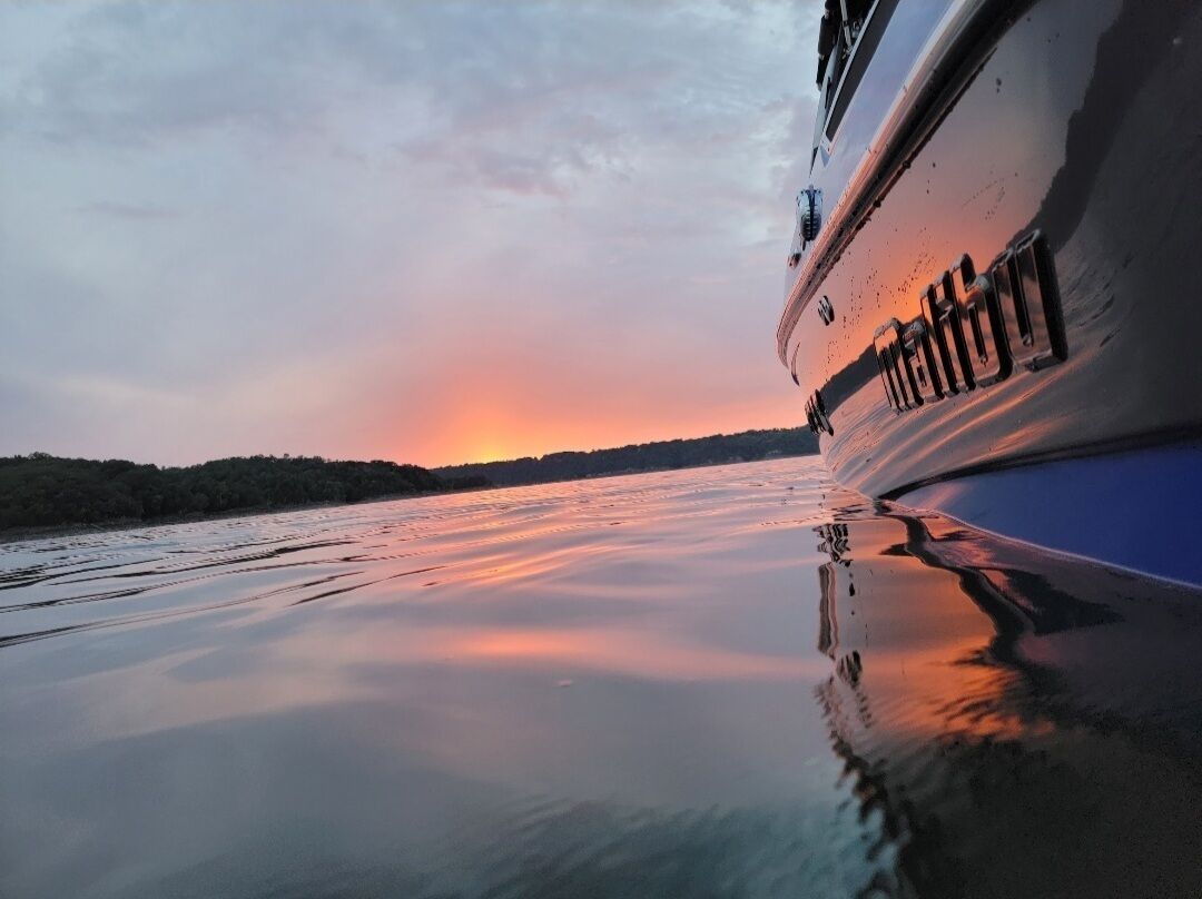 Een boot op kalm water met een ondergaande zon op de achtergrond.