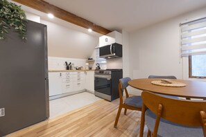 Een moderne keuken met witte kasten, een ingebouwde oven, een magnetron en een eethoek met een houten tafel en stoelen.
