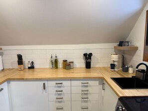 A kitchen with a wooden countertop, white cabinets, and a black stove. - Brilliant 1-bedroom apartment with AC in charming Québec (Québec)