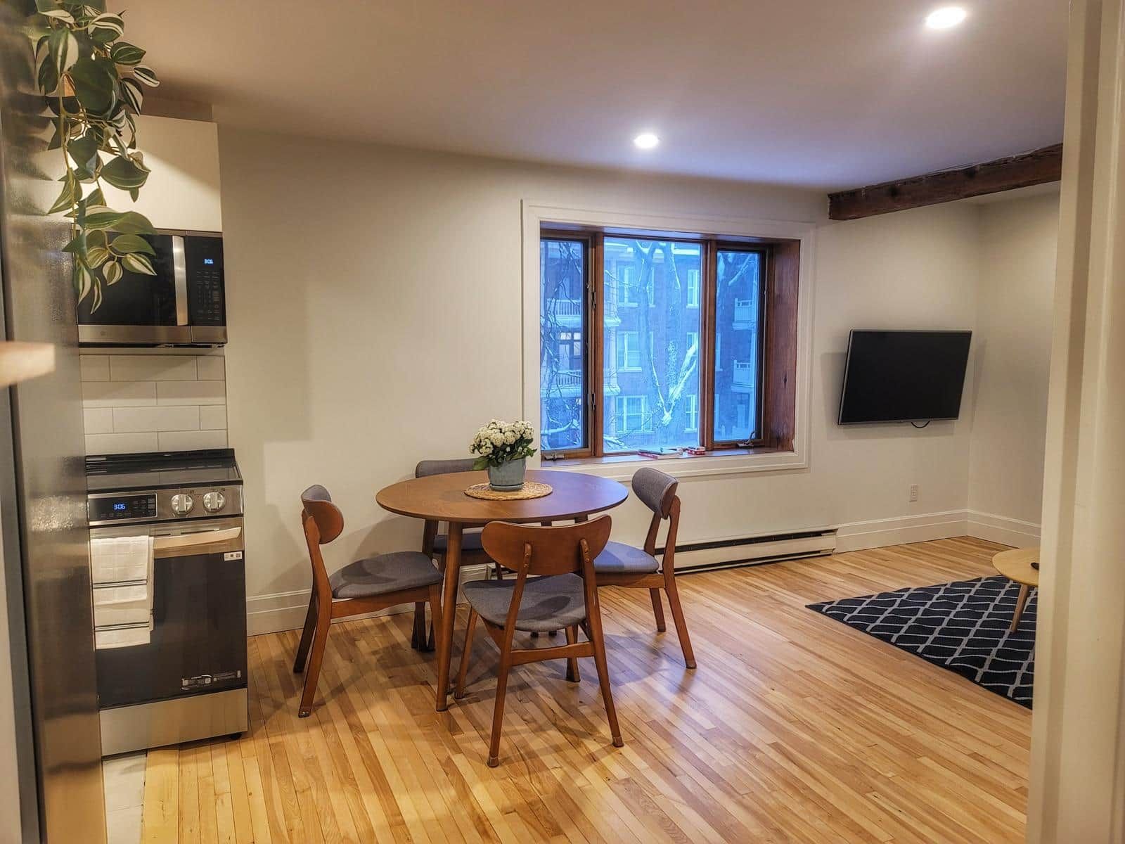 A compact kitchen with a microwave, oven, and a dining area with a table and chairs.