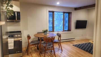 A compact kitchen with a microwave, oven, and a dining area with a table and chairs.