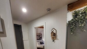 A hallway with wooden flooring leading to a bedroom with a bed and a mounted wall decoration. - Brilliant 1-bedroom apartment with AC in charming Québec (Québec)