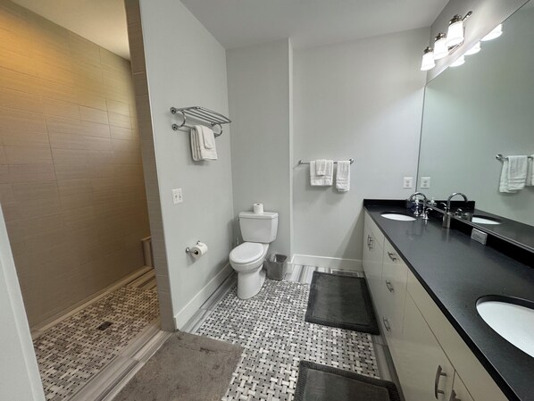 Une salle de bain moderne équipée d’une douche, de toilettes et d’un meuble-lavabo.