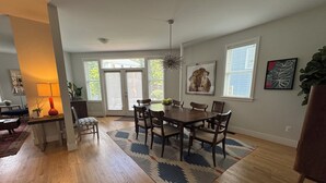 A dining area with a wooden table, chairs, and a patterned rug. There are windows with blinds, a ceiling light, and artwork on the walls. - Adjacent to UVA Grounds, WALKABLE to Scott Stadium, Corner, Downtown (Charlottesville)