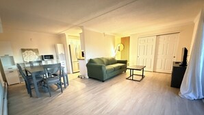 A living room with a dining area, a sofa, a TV, and a door. - Penthouse condo in central Cheesman Park! (Denver)