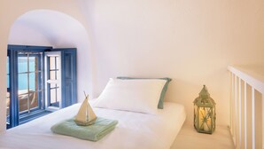 Ein Schlafzimmer mit einem Bett, einer Bootsdekoration, einer Laterne und Blick durch ein Rundbogenfenster.