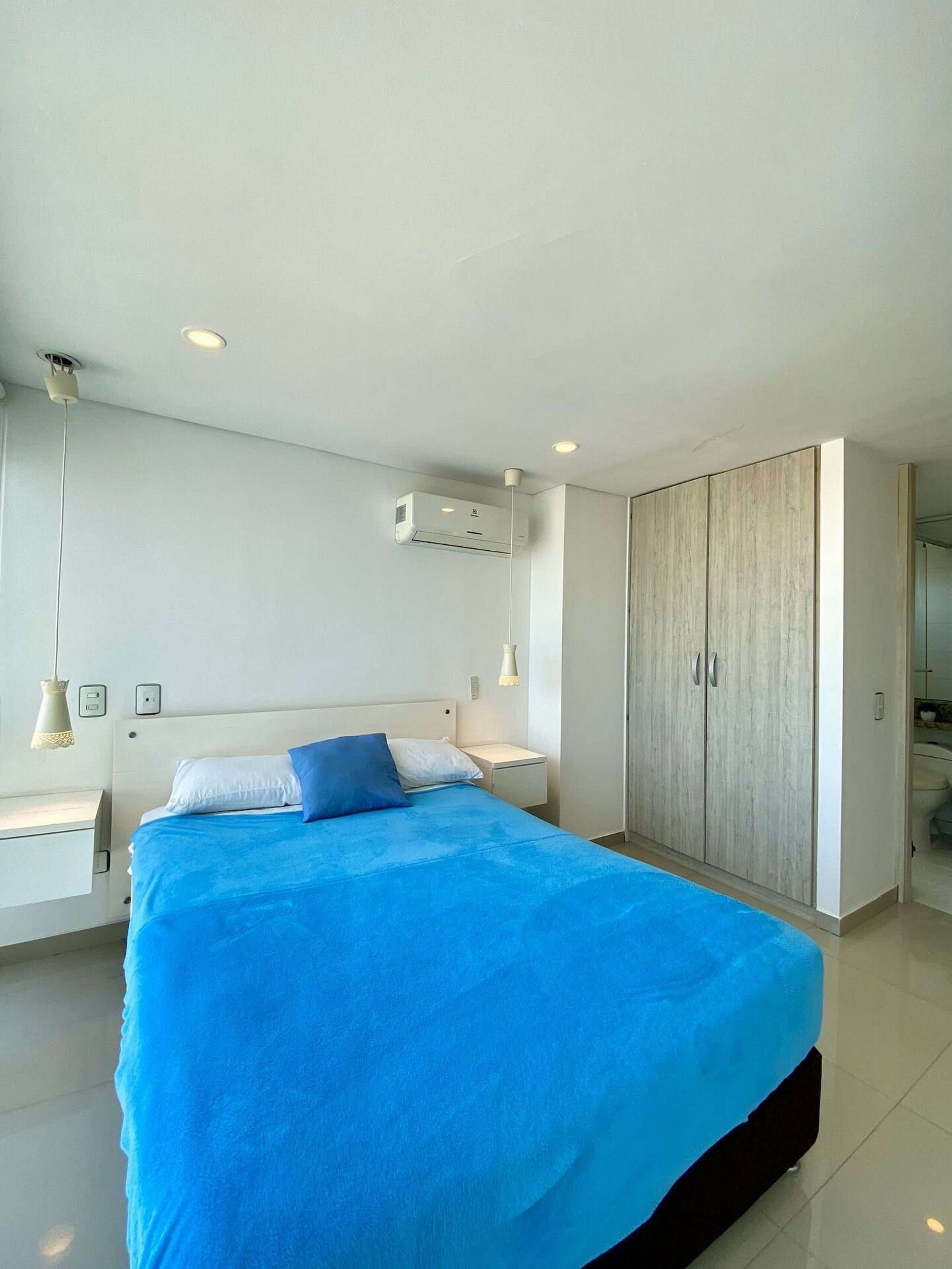 Un dormitorio moderno con una cama grande, un armario y un equipo de aire acondicionado.