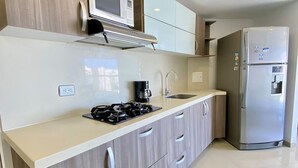 A modern kitchen with a stainless steel refrigerator, a microwave, and a gas stove. - U-GO Torre Areia en Cabo Tortuga (Santa Marta)