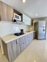 Una cocina moderna con un refrigerador de acero inoxidable, un microondas y una estufa a gas.