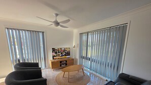 Ein Wohnzimmer mit Fernseher, zwei Sofas, einem Couchtisch und einem Deckenventilator.