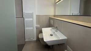 A modern bathroom with a white sink, a toilet, and a towel rack. - Central Düsseldorf Apartment: 2 Beds, WiFi, Elevator – Close to Hbf & Fair (Düsseldorf)