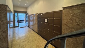 A hallway with a marble floor, a row of brown lockers, and a glass door leading outside. - Central Düsseldorf Apartment: 2 Beds, WiFi, Elevator – Close to Hbf & Fair (Düsseldorf)