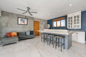 Eine moderne Küche mit Bar, Deckenventilator und Essbereich mit Sofa und Kissen.