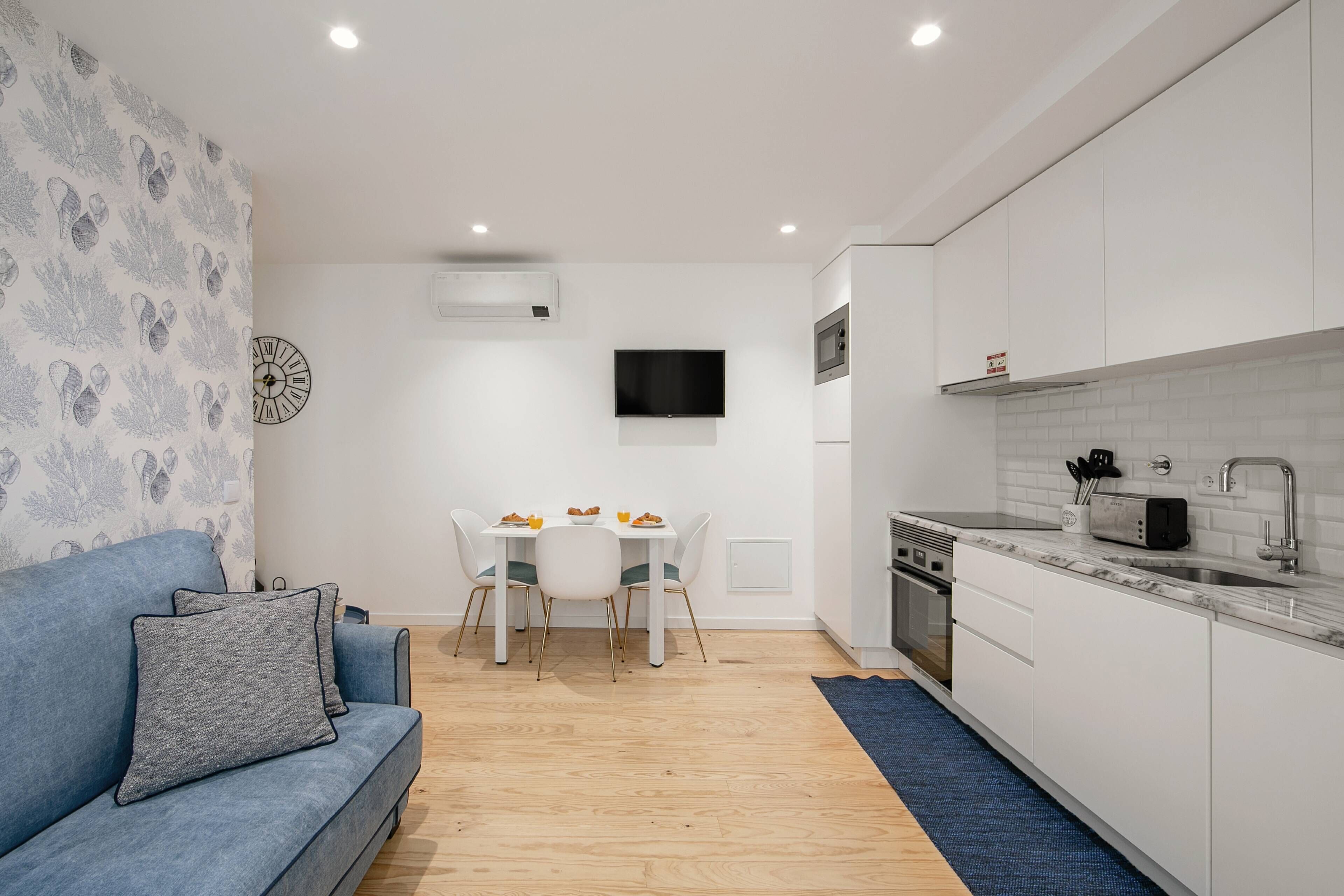 Un espace de vie compact comprenant un canapé, une table à manger et un coin cuisine.