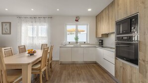 Eine moderne Küche mit Holzschränken, einem eingebauten Ofen und einem Essbereich mit Tisch und Stühlen.