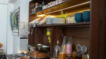 Montaje de bufé con diversos alimentos y bebidas, incluyendo tazones de cereal, un tarro de aceitunas y una bebida rosa.