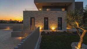 A modern two-story house with a stone facade, a balcony, and a well-lit entrance. - Awesome home in Funtana (Funtana)