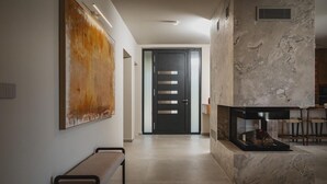 A modern interior with a bench, a fireplace, and a large abstract painting on the wall. - Awesome home in Funtana (Funtana)