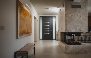 Ein modernes Interieur mit einer Bank, einem Kamin und einem großen abstrakten Gemälde an der Wand.