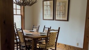 A dining area with a wooden table and chairs, framed artwork on the wall, and a chandelier. - Cashiers, Trillium Lake Glenville Mountain Home 2 bedroom plus kids bunk room (Cashiers)