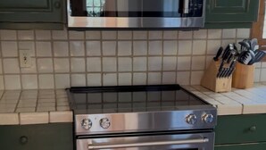 A kitchen with a stainless steel oven and microwave, green cabinets, and a tiled backsplash. - Cashiers, Trillium Lake Glenville Mountain Home 2 bedroom plus kids bunk room (Cashiers)