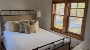 A bedroom with a bed, a ceiling fan, a window, and a bedside table. - Cashiers, Trillium Lake Glenville Mountain Home 2 bedroom plus kids bunk room (Cashiers)