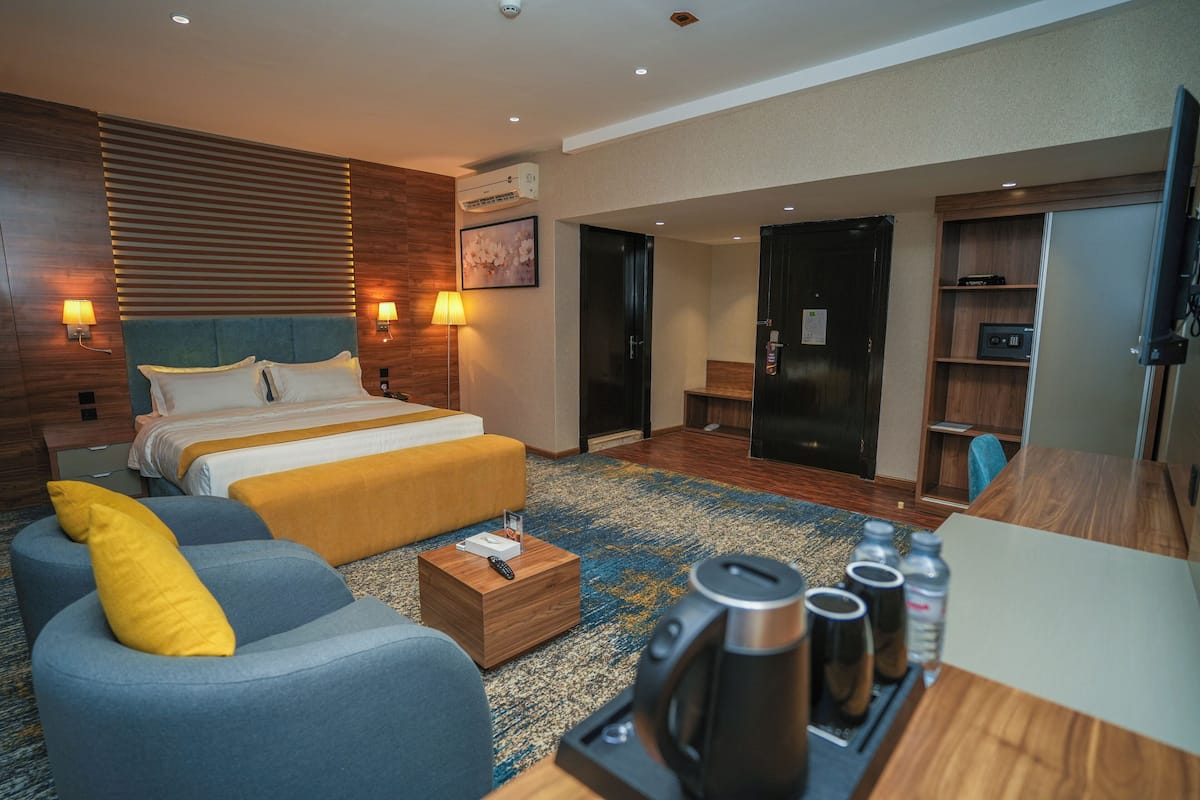Una habitación de hotel con cama, sofá, mesa de centro, televisor y minibar.