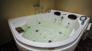 A white bathtub with a built-in seat, a handheld showerhead, and a control panel. - Haven Plaza Hotel Riyadh  (Riyadh)