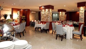 A restaurant with multiple tables, each set with white tablecloths and red napkins. - Haven Plaza Hotel Riyadh  (Riyadh)