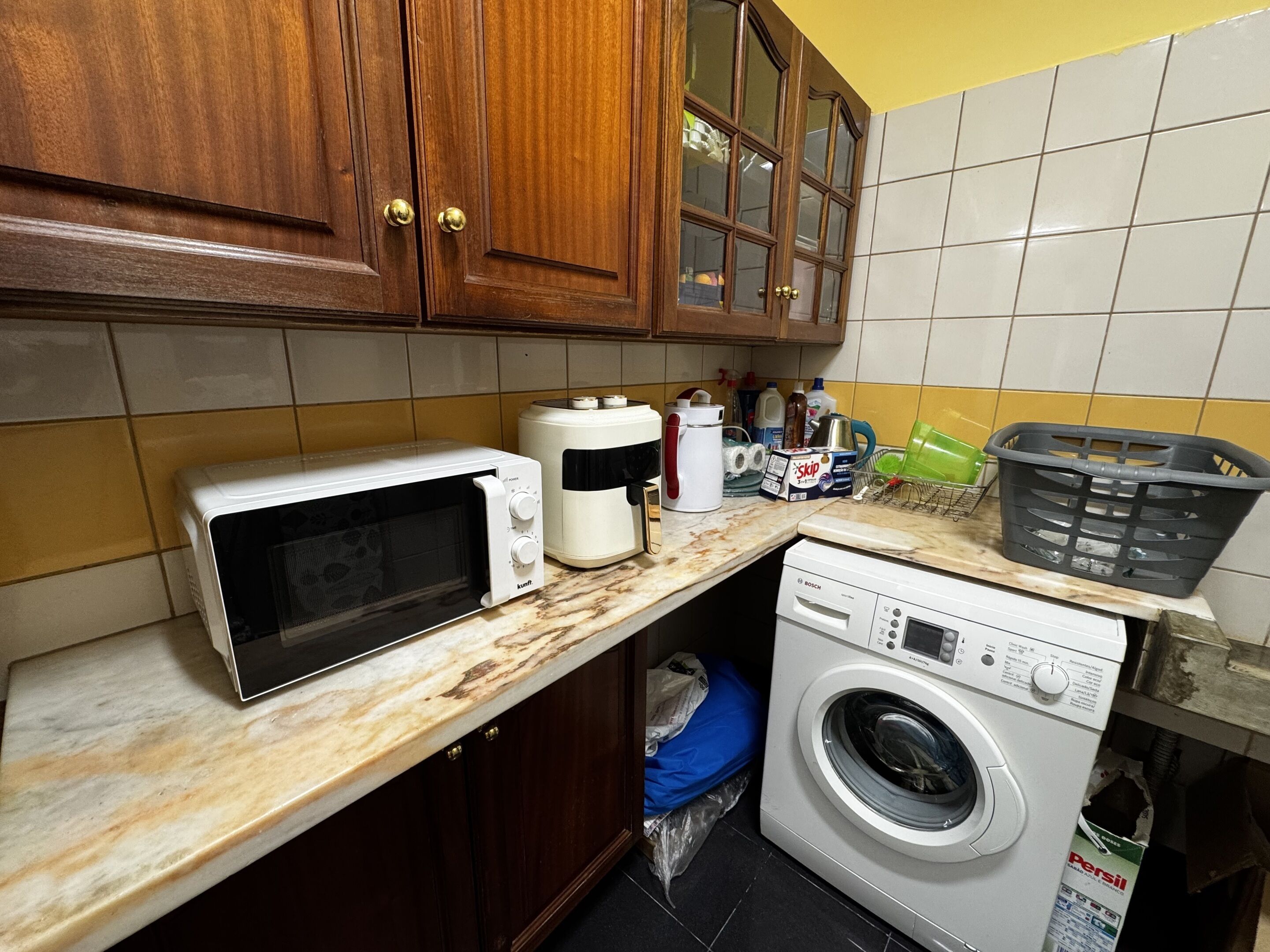 A kitchen with a microwave, coffee maker, and washing machine.