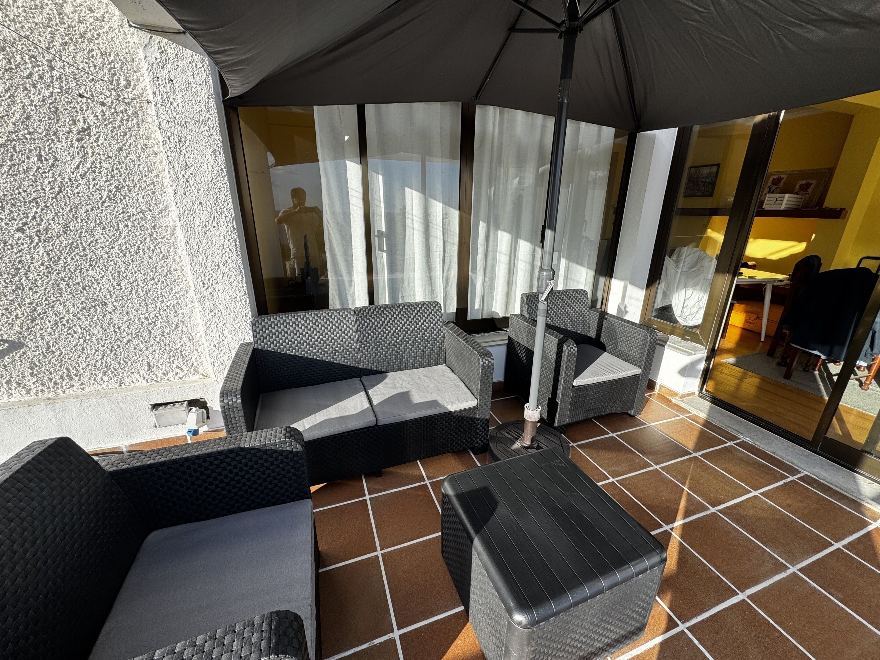 A covered outdoor seating area with wicker furniture and a tiled floor.