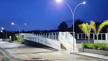 A modern bridge with metal railings and a staircase leading to a building.