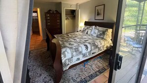 A bedroom with a bed, dresser, and a door leading to a bathroom.