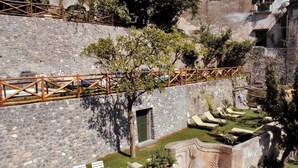 A stone building with a wooden bridge, outdoor seating, and a stone wall.