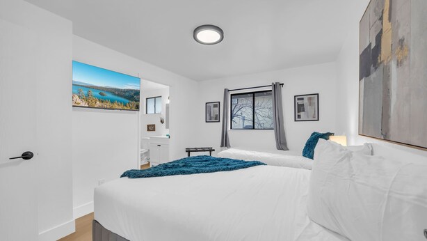 A bedroom with a large bed, a window with curtains, a painting on the wall, and a small desk. - Tranquil Oasis Duplex/5Baths/Sleeps 15 (Reno)