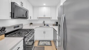 A modern kitchen with white cabinets, stainless steel appliances, and a central island. - Tranquil Oasis Duplex/5Baths/Sleeps 15 (Reno)