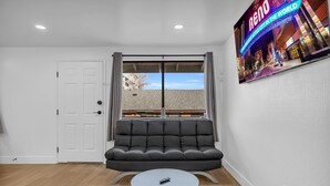 A modern living room with a sofa, a small table, and a large window. - Tranquil Oasis Duplex/5Baths/Sleeps 15 (Reno)