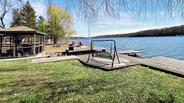 A lakeside park with a gazebo, swing set, and picnic area. - Luxury Lake House - Hot Tub - Fire Pit - BBQ -Dock (Hasting)