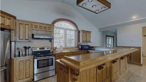 A spacious kitchen with wooden cabinets, stainless steel appliances, and a large island. - Luxury Lake House - Hot Tub - Fire Pit - BBQ -Dock (Hasting)