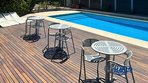 A swimming pool with lounge chairs and tables on a wooden deck, surrounded by a fence and buildings. - Apartment Alassio 2 rooms (Buenos Aires)