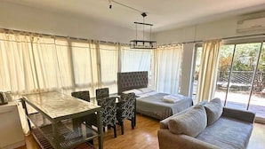 A modern living room with a sofa, a dining table with chairs, and a bed. - Apartment Alassio 2 rooms (Buenos Aires)