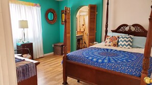 Ein Schlafzimmer mit einem Himmelbett, einem Holztisch, einem Stuhl, einem Spiegel und einem Vorhangfenster.