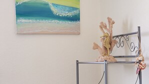 Ein Metallregal mit Dekorationsobjekten und einem Strandbild an der Wand.