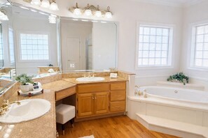 Ein geräumiges Badezimmer mit zwei Waschbecken, einem großen Spiegel und einer Badewanne.