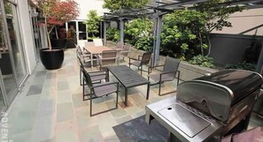 An outdoor patio with a barbecue grill, seating area, and potted plants. - Bright 1 Bedroom Condo in the Heart of the City! (Vancouver)