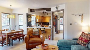 Un amplio espacio de estar con una mesa de comedor, un sofá de cuero y una cocina al fondo.