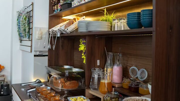 A buffet setup with various food items and drinks, including bowls of cereal, a glass jar of olives, and a pink drink. - Family Apartment - - Bed and Breakfast in Cusco (Cusco)